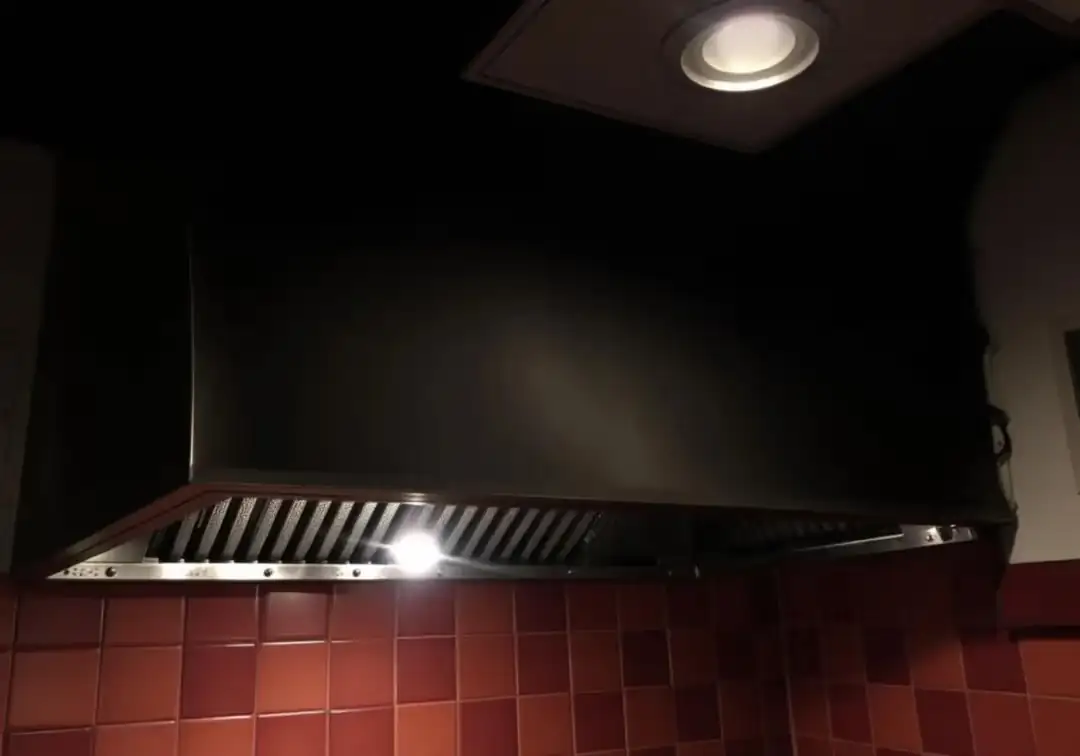 Afzuigkap boven een kookplaat in een donkere keuken